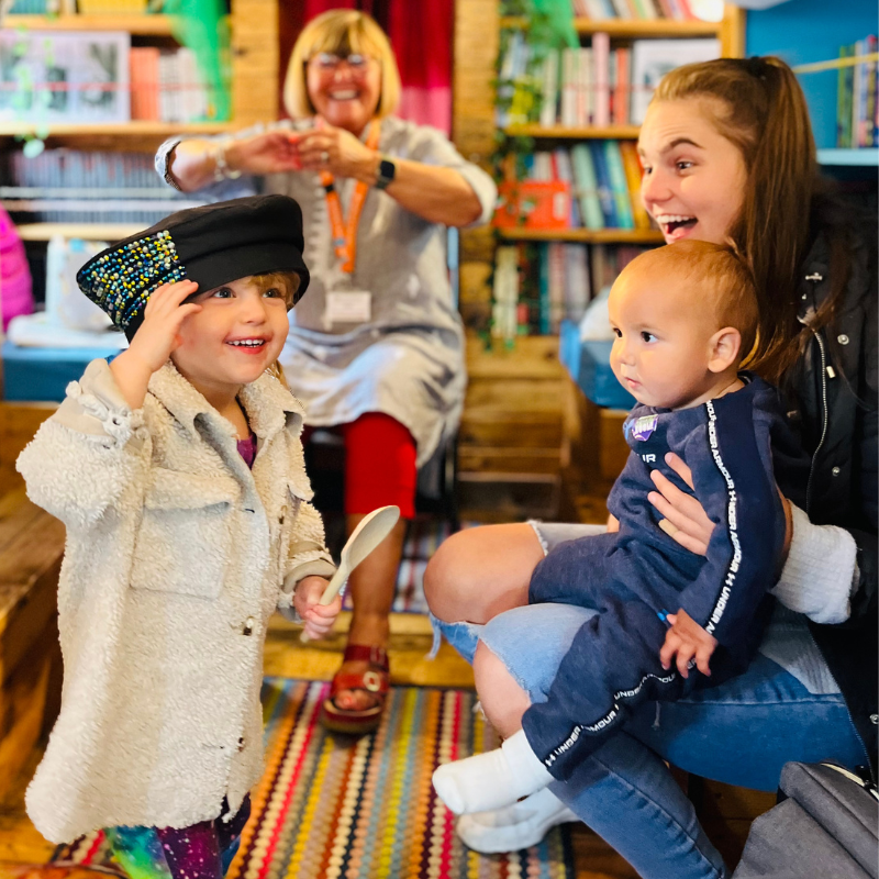 Family laughing while playing dress up in the Bradford Stories Bus