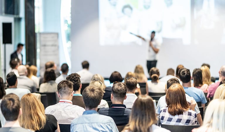 A crowd of people looking at a speaker during a conference