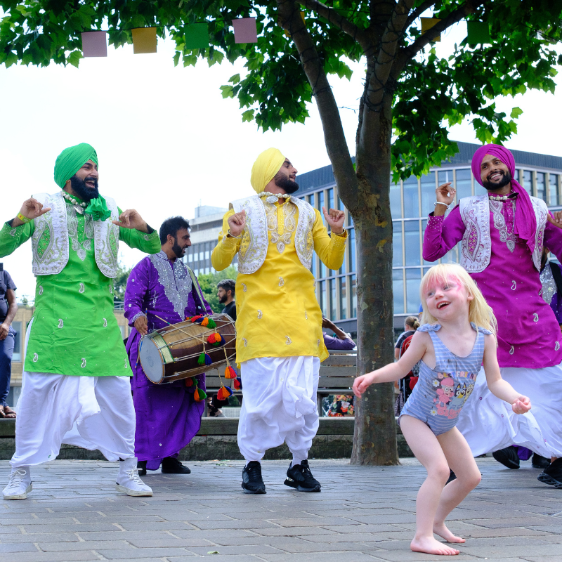A young child dances alongside Punjabi Roots in City Park